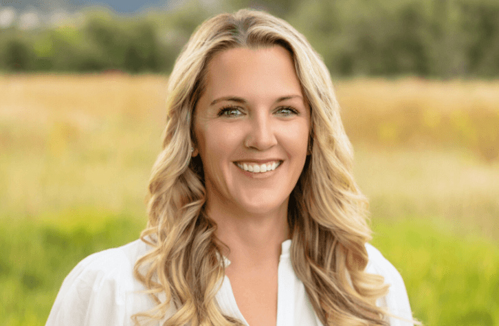 Smiling woman outdoors in a grassy field.