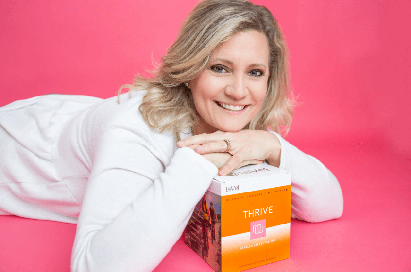 Woman with THRIVE box on pink background.